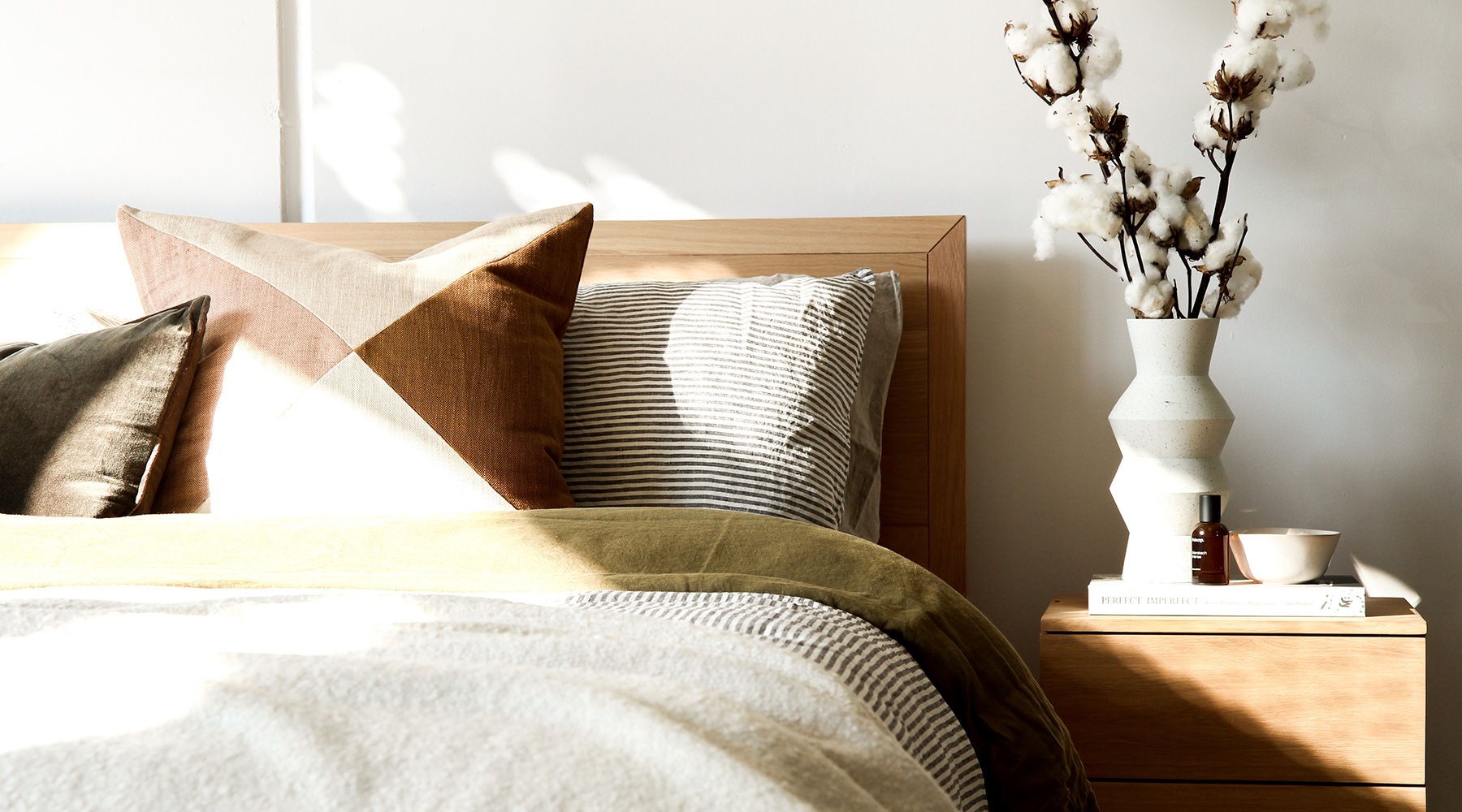 bed with pillows next to table with flowers